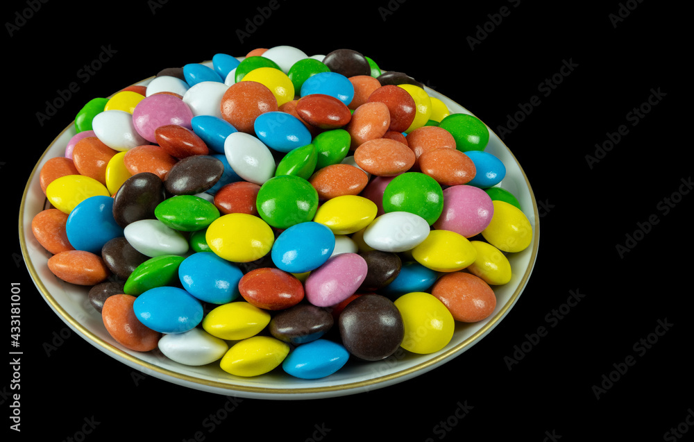 Round milk chocolate balls on a plate on a black background Round milk chocolate balls on a plate on a black background