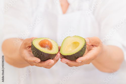 Hands holding a fresh avocado cut in half: Selective focus and close up. Healthy food concept.