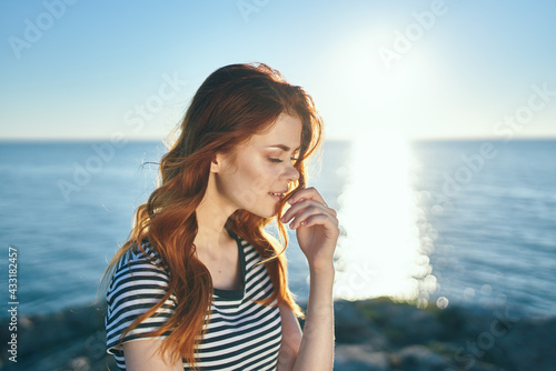 woman in summer walks on the beach near the sea and sunset in the background