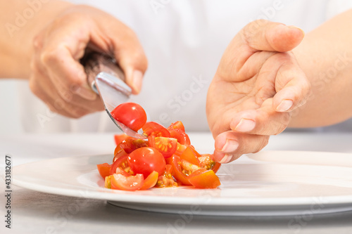 Hands dropping freshly cut tomatoes on a plate