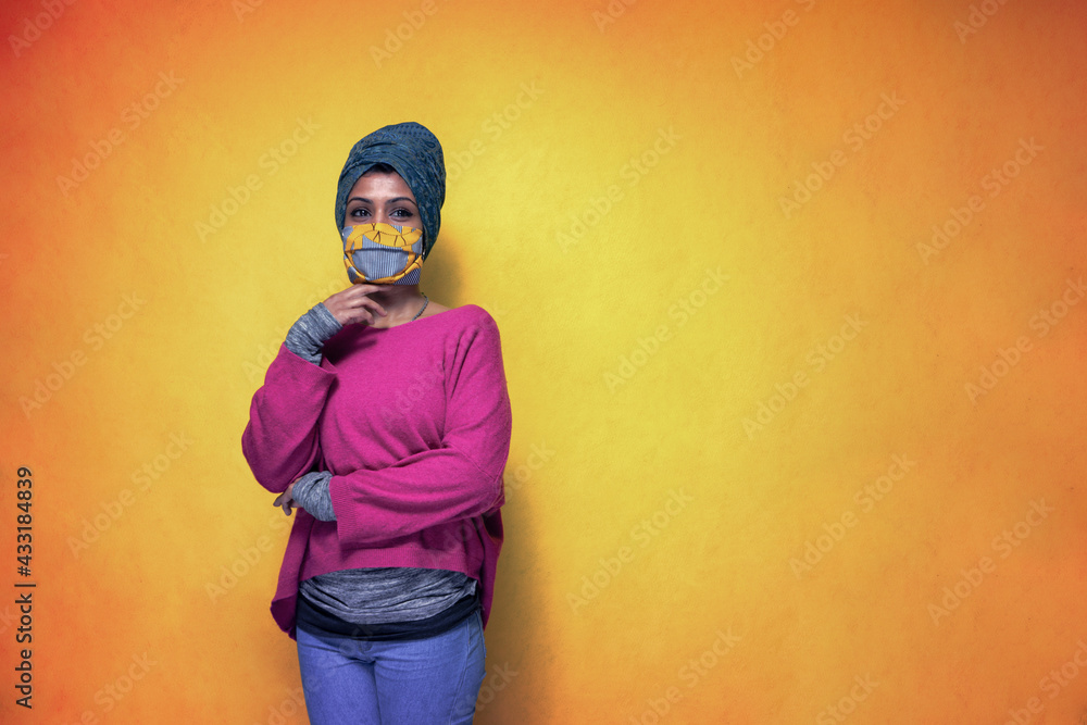 Beautiful young indian woman posing with covid 19 mask protection wearing a turban - Pretty Sri Lanka girl uses protection from pandemic flue posing with a yellow background Beautiful young indian woman posing with covid 19 mask protection wearing a turban - Pretty Sri Lanka girl uses protection from pandemic flue posing with a yellow background
