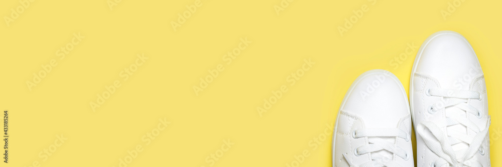 White sneakers on yellow background top view flat lay. Stylish youth women's leather sneakers, sports shoes, genuine leather footwear. Minimalistic shoe store advertising fashion style Shoe background White sneakers on yellow background top view flat lay. Stylish youth women's leather sneakers, sports shoes, genuine leather footwear. Minimalistic shoe store advertising fashion style Shoe background