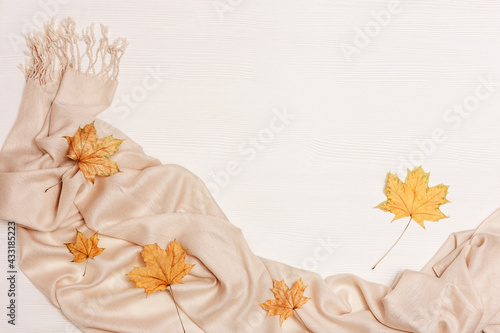 Yellow autumn leaves flat lay on white wooden background with copy space. Natural leaves of maple tree and cozy warm palantine, autumnal theme. Top view. photo