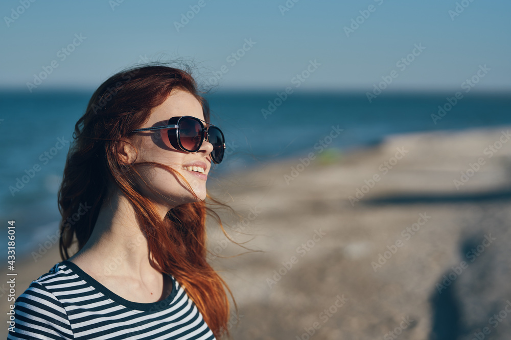 woman in glasses and in a striped T-shirt at sunset or there near the sea view from the balcony woman in glasses and in a striped T-shirt at sunset or there near the sea view from the balcony