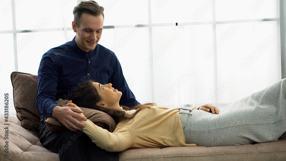 couple in love lying on sofa talking  together on window