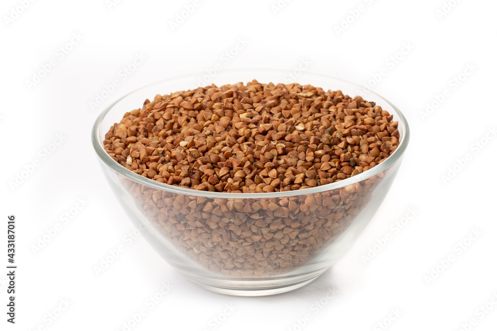 Dry buckwheat in white ceramic bowl isolated on white. Spilled buckwheat. Dry buckwheat in white ceramic bowl isolated on white. Spilled buckwheat.