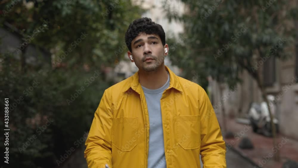 Handsome man in earphones walking on street with map Handsome man in earphones walking on street with map