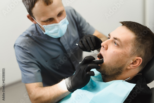 A male dentist examines the bracket system before adjusting it. Consultation and control examination at the dental clinic