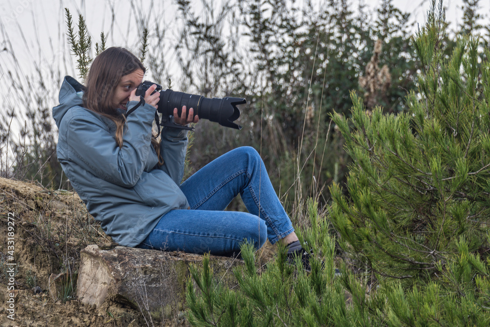 Young girl photographer with a camera and a large telephoto lens photographing wildlife Young girl photographer with a camera and a large telephoto lens photographing wildlife