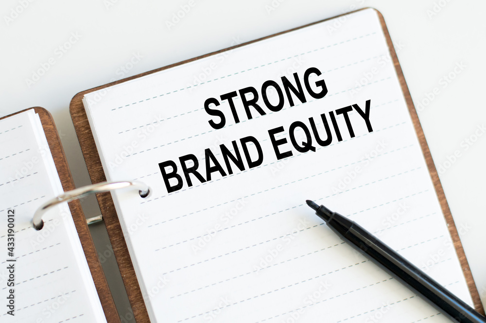 Text STRONG BRAND EQUITY on notepad on white background next to black marker Text STRONG BRAND EQUITY on notepad on white background next to black marker