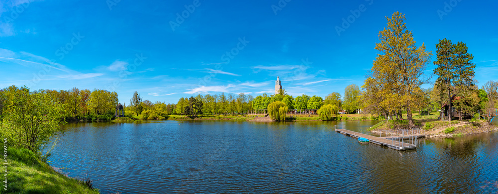 Fototapeta premium Panoramic view over city park and lake in Spring colors at sunny day with blue sky, Magdeburg, Germany.