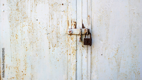 background of very old metal rusty grey garage door with handle and barn lock
