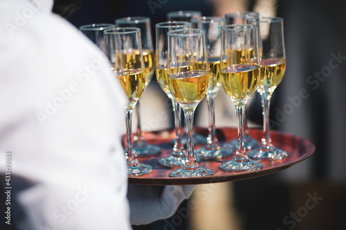 Shallow depth of field (selective focus) details with a waiter walking around and giving sparkling wine to the guests of an event.