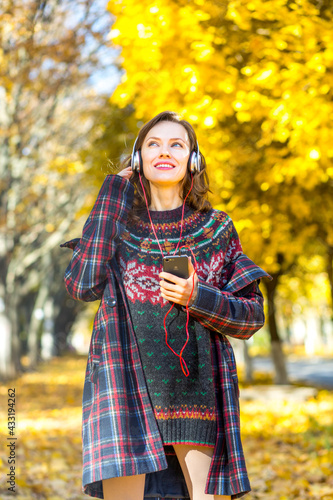  Beautiful autumn woman in autumn yellow street listening music, making selfie