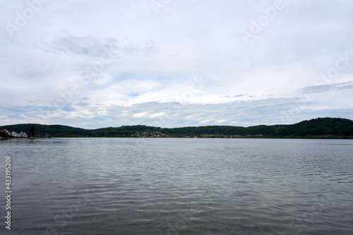 panaroma shot of lake constance with clouds, mountains and trees