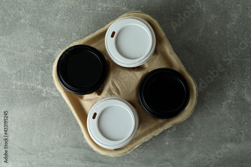 Cup holder with coffee cups on gray textured background