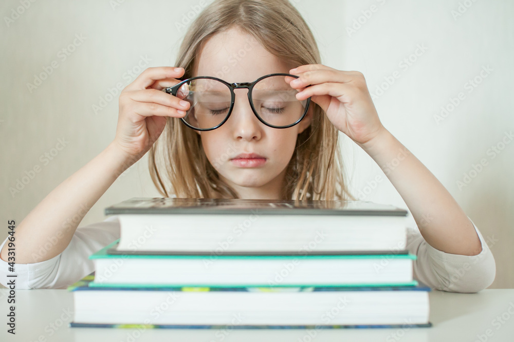 Little girl with glasses does homework, reads books. High quality photo Little girl with glasses does homework, reads books. High quality photo