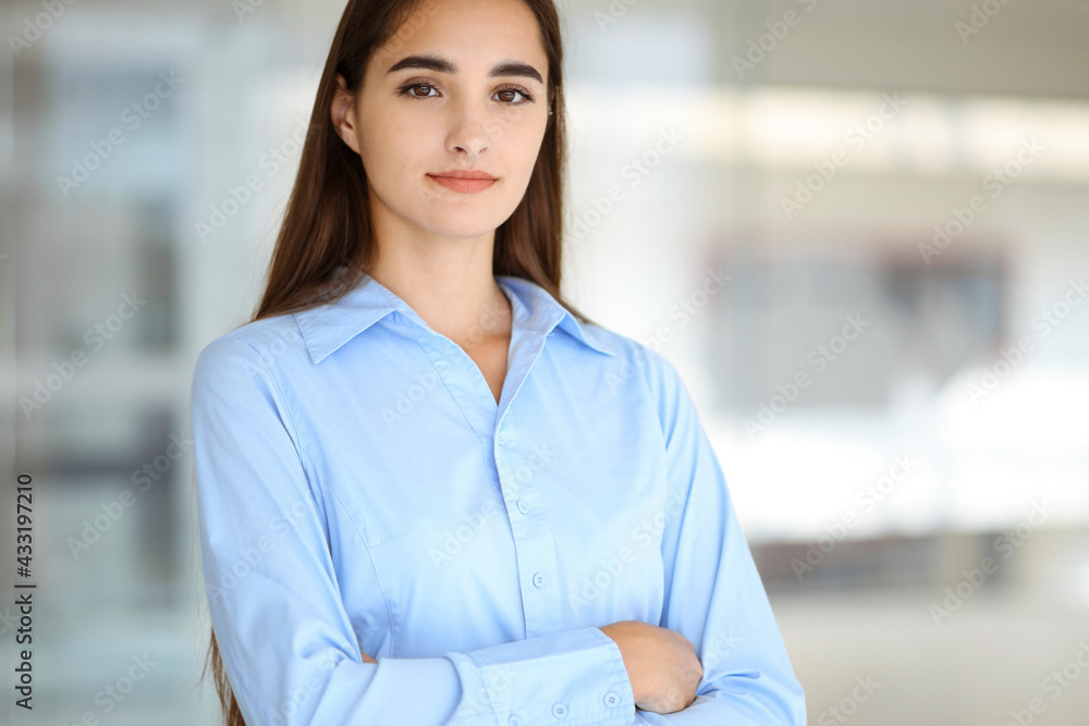 A friendly young dark hair businesswoman or female student is standing with some papers in the office A friendly young dark hair businesswoman or female student is standing with some papers in the office
