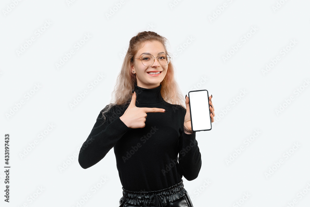 Portrait of cute young woman pointing finger on mobile phone screen, standing against white background Portrait of cute young woman pointing finger on mobile phone screen, standing against white background
