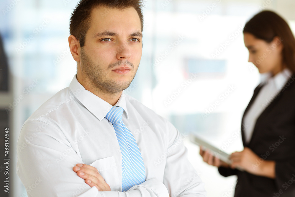 Portrait of a self-confident middle-aged businessman, standing with his colleague in the background. Business concept Portrait of a self-confident middle-aged businessman, standing with his colleague in the background. Business concept