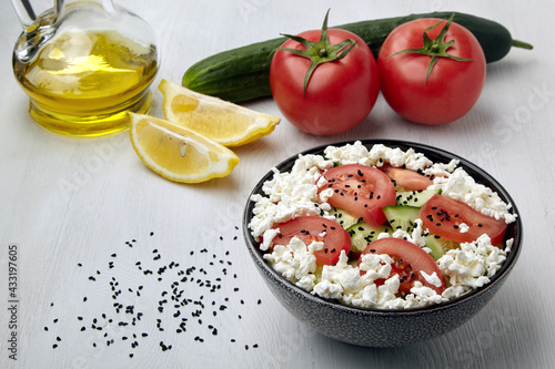 Chopped tomatoes and cucumbers with cottage cheese and black cumin seeds photo