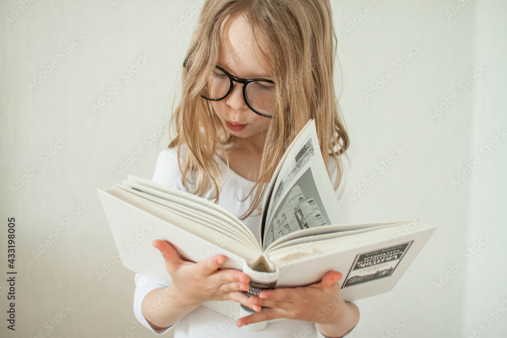 Little girl with glasses does homework, reads books. High quality photo Little girl with glasses does homework, reads books. High quality photo