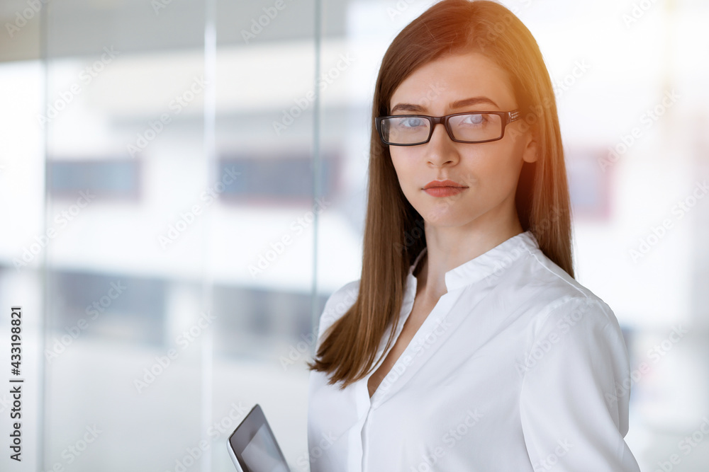 Beautiful female specialist with tablet computer standing in sunny office and smiling charmingly. Business people concept Beautiful female specialist with tablet computer standing in sunny office and smiling charmingly. Business people concept