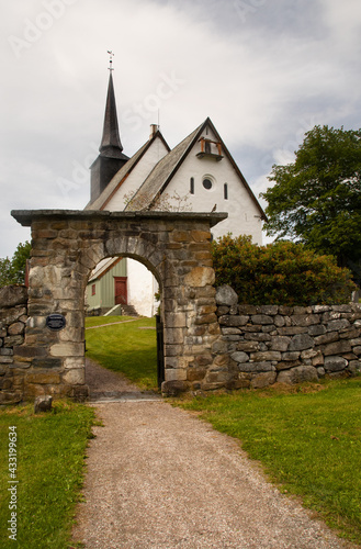 Tingvoll Church, Tingvoll, Norway. The 800 years old Romanesque style church is surrounded by a beautiful stone fence with a beautiful stone archway. 