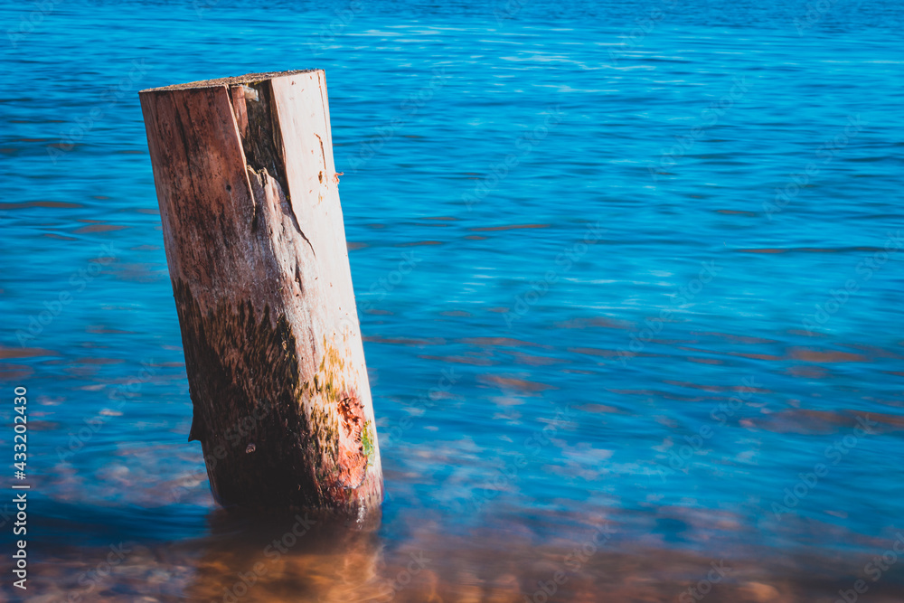 Wooden pile washed by the blue waters of the lake with the mountains in the background Wooden pile washed by the blue waters of the lake with the mountains in the background