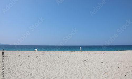 beach made of white pebbles and a blue sea on a clear summer day