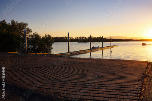  Fishmermen returning to a small boatramp with a corrugated and textured slipway at sunset.