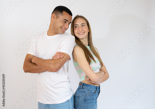 Happy loving couple. Studio shot of beautiful young couple in casual clothes standing back to back and smiling