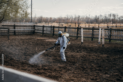 A man in a special white overalls disinfects the territory