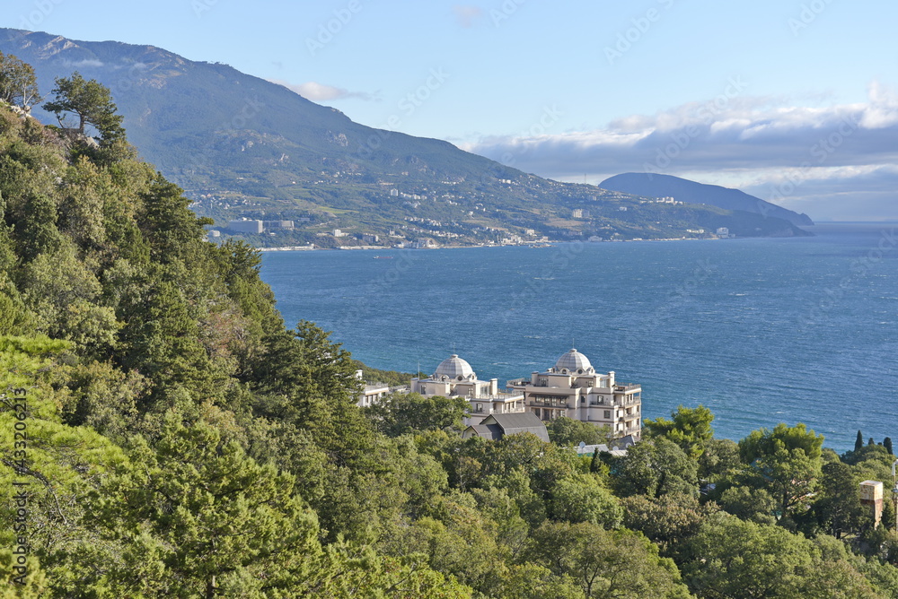 Yalta, Crimea - 10.16.2015 : Different types of vegetation in a mountainous area against the background of buildings near the Black Sea coast.