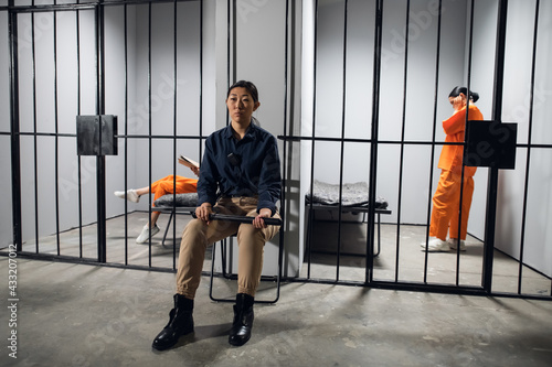 A typical day in a women's prison. A bored female guard in uniform sits near the cells with female prisoners.