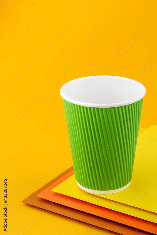 Empty paper green cup on colorful yellow background. Mockup. Coffee to go. Space for text. Close up Empty paper green cup on colorful yellow background. Mockup. Coffee to go. Space for text. Close up