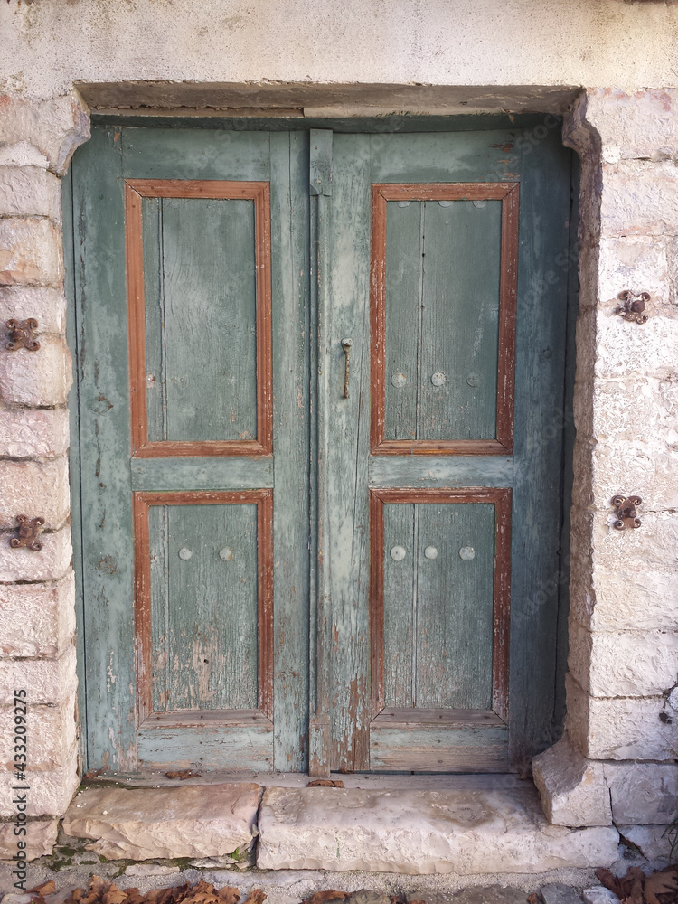 An old wooden door of an abandoned house. In green-brown color. Faded. At a traditional village, near Vikos gorge. An old wooden door of an abandoned house. In green-brown color. Faded. At a traditional village, near Vikos gorge.
