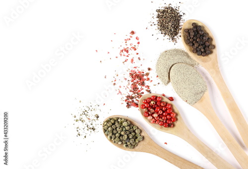 Ground peppercorn mix, white, black, green and red pepper piles in wooden spoons isolated on white background, top view