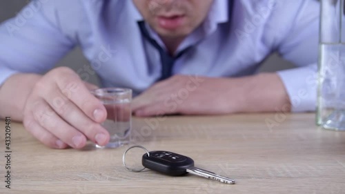 A Man Sitting  with Car Keys on the Table Drinking Alcohol. Alcohol abuse, drunk driving and people concept