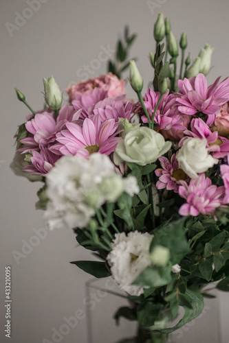 Beautiful bouquet of spring flowers. Delicate bouquet of pink and white flowers. Pink peony roses, purple chrysanthemum, white roses. Spring colors on grey background.