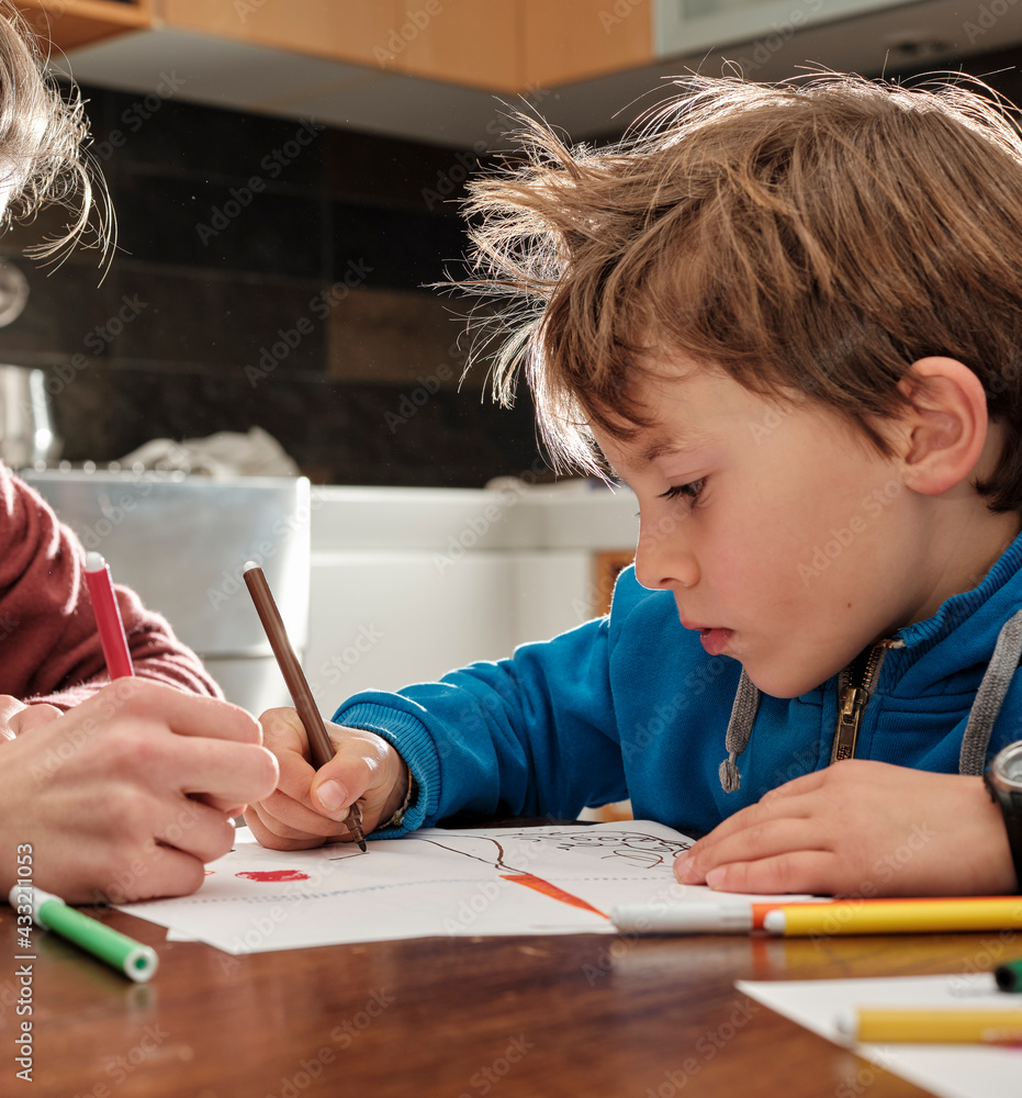 Children draw on sheets of paper with pencils and markers, sitting at the table in the kitchen at home. Children draw on sheets of paper with pencils and markers, sitting at the table in the kitchen at home.