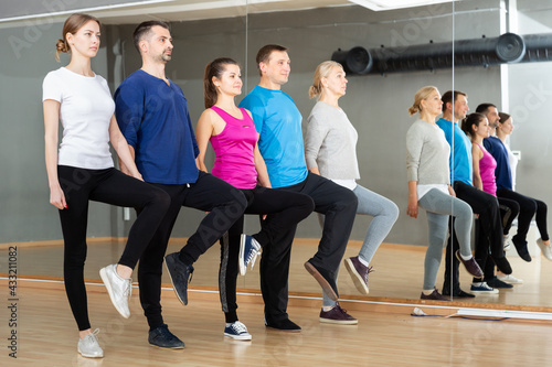 Positive adults forming line while rehearsing traditional Irish stepdance in dance studio