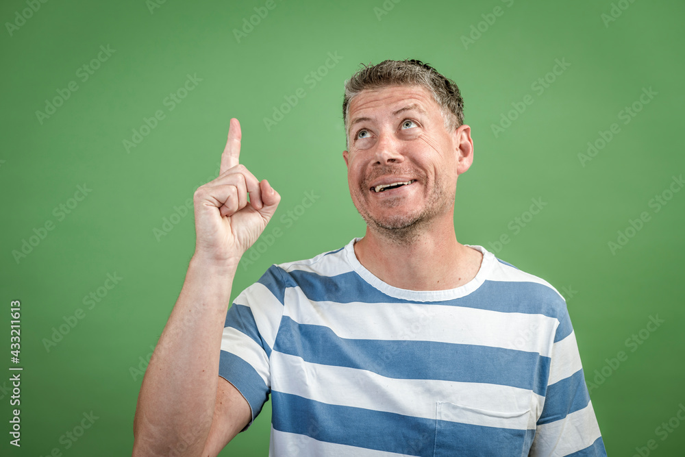 good looking Man in early 40s with gray hair and three day beard with white blue striped t-shirt posing in front of green background good looking Man in early 40s with gray hair and three day beard with white blue striped t-shirt posing in front of green background