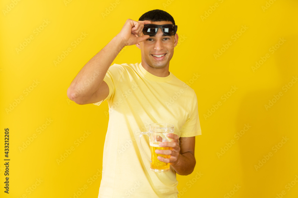 Young man in sunglasses with beer isolated over yellow background