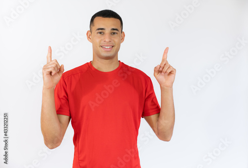 Attractive young man in casual t-shirt pointing up with his fingers isolated over white background