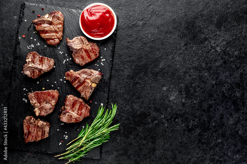 several mini Grilled beef T-bone steaks on stone background with copy space for your text