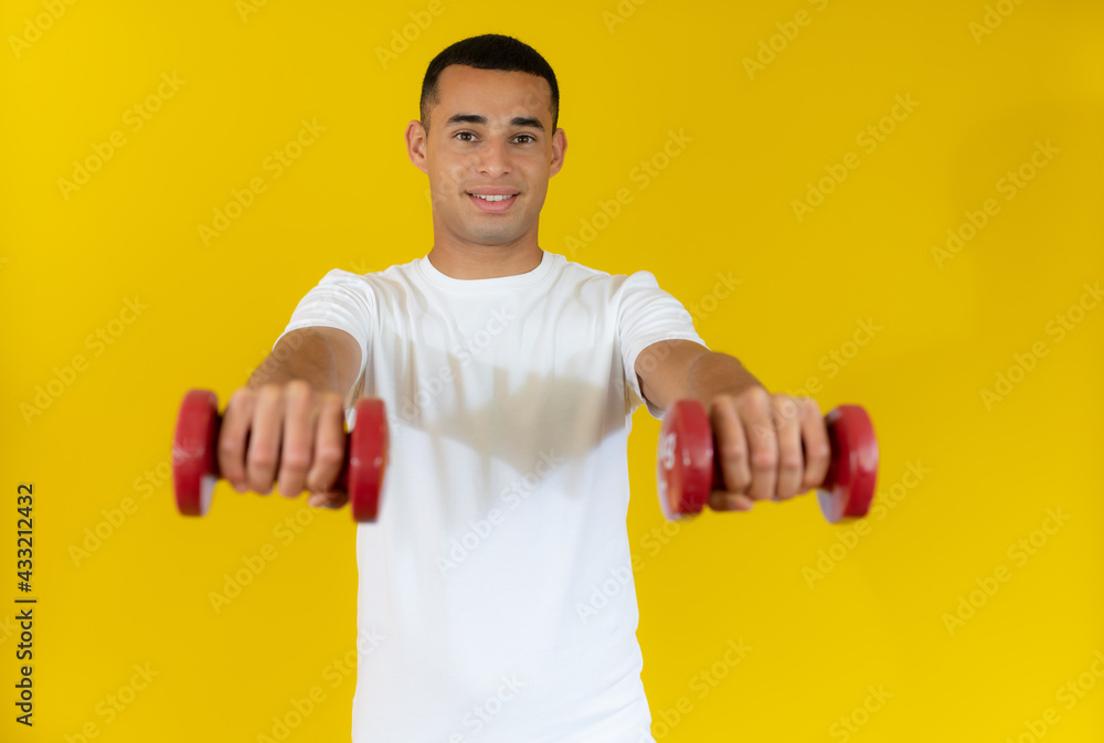 smiling handsome sportsman in white t-shirt holding dumbbell isolated over yellow background. smiling handsome sportsman in white t-shirt holding dumbbell isolated over yellow background.