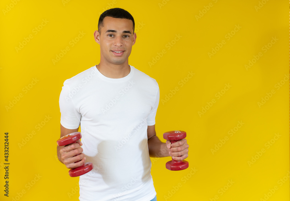 smiling handsome sportsman in white t-shirt holding dumbbell isolated over yellow background. smiling handsome sportsman in white t-shirt holding dumbbell isolated over yellow background.