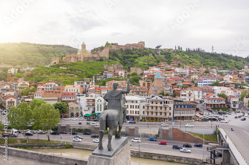 aerial photo Tbilisi Georgia old city. Drone flies next to  Metekhi Cathedral and monument of King Vakhtang Gorgasali. Spring cloudy sky. Panoramic view to old town with traditional buildings photo