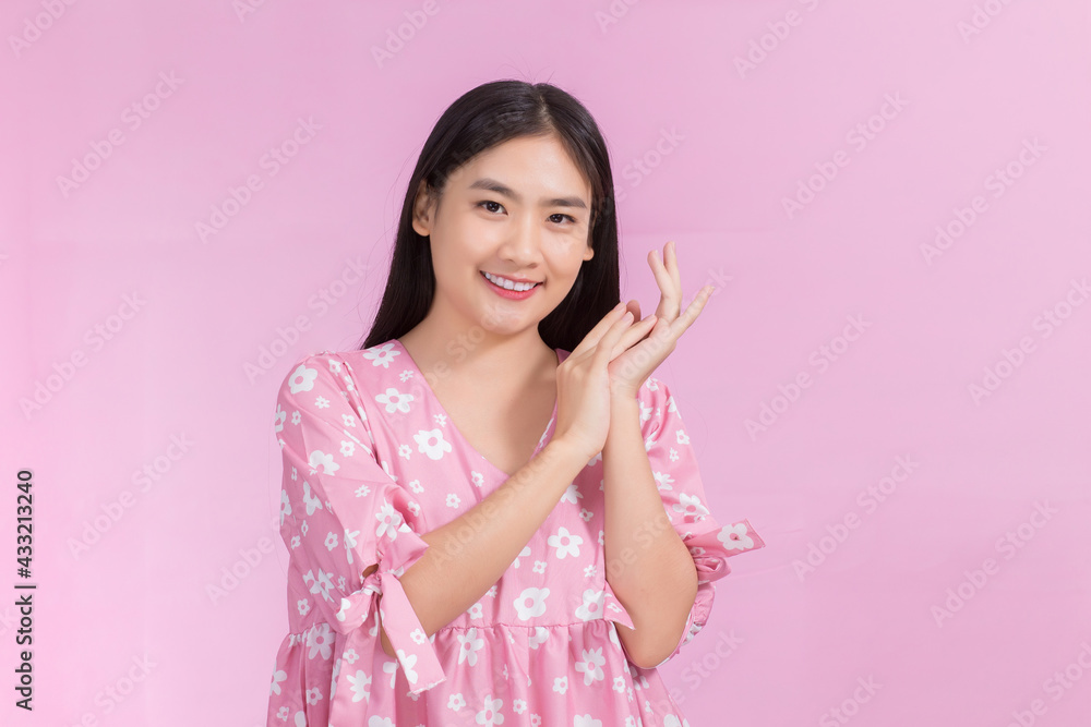 Portrait Asian beautiful woman in pink dress and black long hair. Her hands touch cheek, smile, show beautiful skin on pink background. Portrait Asian beautiful woman in pink dress and black long hair. Her hands touch cheek, smile, show beautiful skin on pink background.